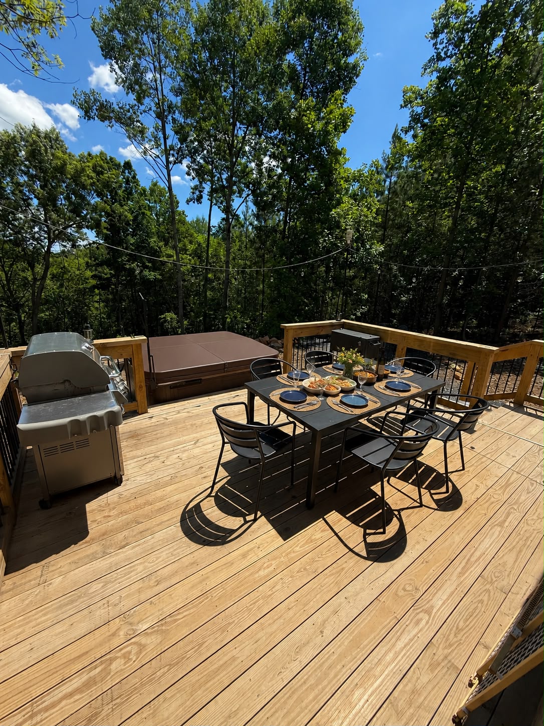 Rear deck with dining set and hot tub by day
